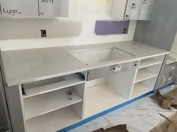 Bancada con hueco de fregadero. Encimera gris claro con veta suave sobre muebles bajos, con el hueco del fregadero y la pared aún por rematar.