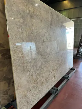Tablero pulido gris y beige en caballete. Tablero pulido en tonos gris y beige con finas vetas ocres, apoyado en un caballete dentro de una nave.
