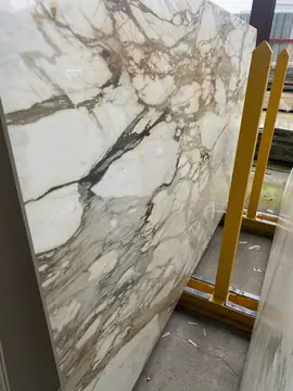 Tablero blanco con vetas grises y ocres. Tablero pulido blanco con vetas grises y ocres, apoyado en un caballete amarillo de almacén.