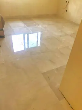 Pavimento pulido en tono crema en una estancia. Estancia con pavimento de piezas grandes pulidas en tono crema; la luz de la ventana se refleja en el suelo.