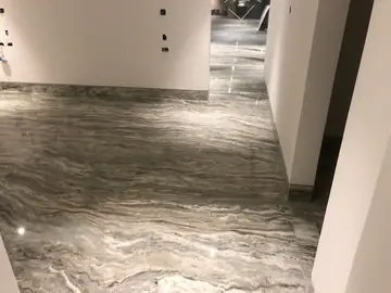 Pasillo con pavimento pulido veteado. Pavimento pulido en gris con vetas onduladas a lo largo de un pasillo, con las paredes aún pendientes de terminar.