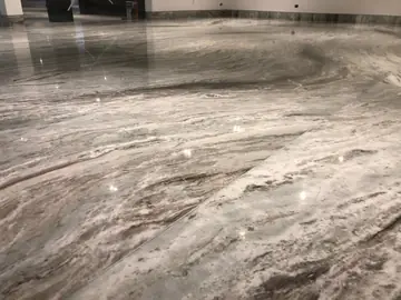 Detalle de pavimento veteado. Piezas pulidas en gris y blanco con vetas onduladas y una junta apenas visible entre losas.