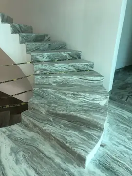 Escalera curva con peldaños veteados. Tramo de escalera curva con huellas y tabicas en gris veteado, protegido con cinta de balizamiento.