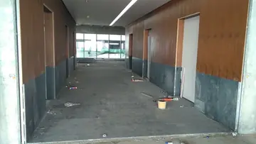 Pasillo con pavimento y zócalo oscuros. Pasillo con pavimento y zócalo oscuros ya colocados y paneles en tono madera, a falta de limpieza final.
