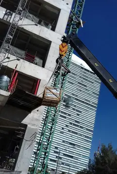 Descarga de material en plataforma volada. La grúa deposita una caja de material en una plataforma de descarga de la estructura.