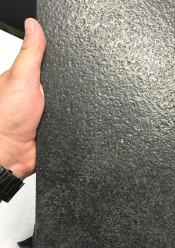 Pieza oscura de superficie rugosa. Detalle de una pieza oscura de superficie rugosa sostenida en la mano.