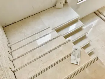 Peldaños con ranuras antideslizantes. Vista cenital de un tramo con huellas en tono crema y tres ranuras en el borde de cada peldaño.
