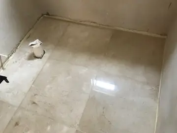 Pavimento pulido en tono crema con veta. Estancia con piezas grandes ya colocadas y pulidas, a falta de rematar paredes e instalaciones.