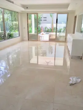 Salón con pavimento pulido en tono crema. Estancia amplia con piezas grandes y acabado brillante que refleja el ventanal y la terraza.