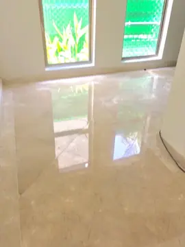 Pavimento pulido bajo dos ventanas. Piezas en tono crema con veta y brillo que reflejan la luz de las ventanas.
