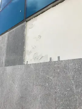 Aplacado gris con grapas de anclaje. Detalle del aplacado gris con veta blanca junto a las grapas metálicas que recibirán la siguiente pieza.