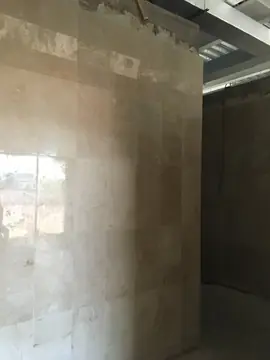 Revestimiento en tono crema en muro interior. Muro revestido con piezas pulidas en tono crema con veta, con la parte alta aún pendiente de rematar.