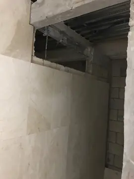 Revestimiento crema en piezas grandes. Muro interior revestido con piezas grandes en tono crema con veta, junto a un hueco aún sin rematar.