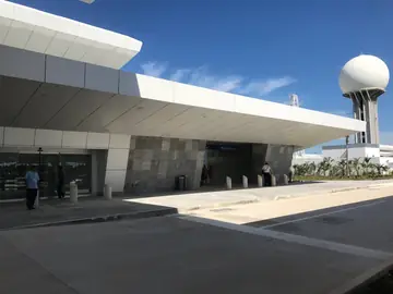 Acceso con aplacado gris bajo marquesina. Fachada de acceso con aplacado gris en piezas de varios formatos bajo una marquesina blanca volada.