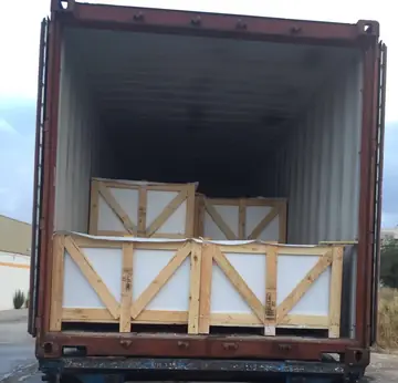 Cajas de madera cargadas en contenedor. Cajas de madera con poliestireno estibadas en dos filas en la boca de un contenedor abierto.
