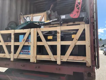 Herramientas y cajas de material en contenedor. Cajas de madera con material y maletas de herramientas, una carretilla y maquinaria cargadas en la boca del contenedor.