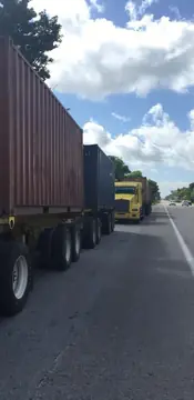 Camiones con contenedores en el arcén. Camiones con contenedores detenidos en fila en el arcén de una carretera.