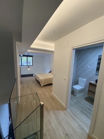 Distribuidor con barandilla. Planta superior con barandilla de vidrio, dormitorio al fondo y baño a la derecha.