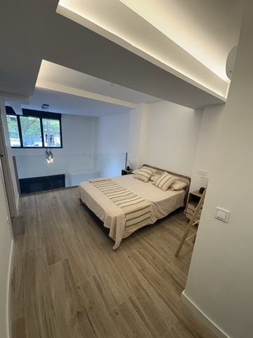 Dormitorio con luz indirecta. Dormitorio con la cama vestida, suelo de porcelánico imitación madera y falso techo de pladur escalonado con LED oculto.