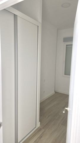 Armario empotrado. Frente de armario empotrado de suelo a techo, con hojas correderas blancas y perfiles de aluminio a la vista.