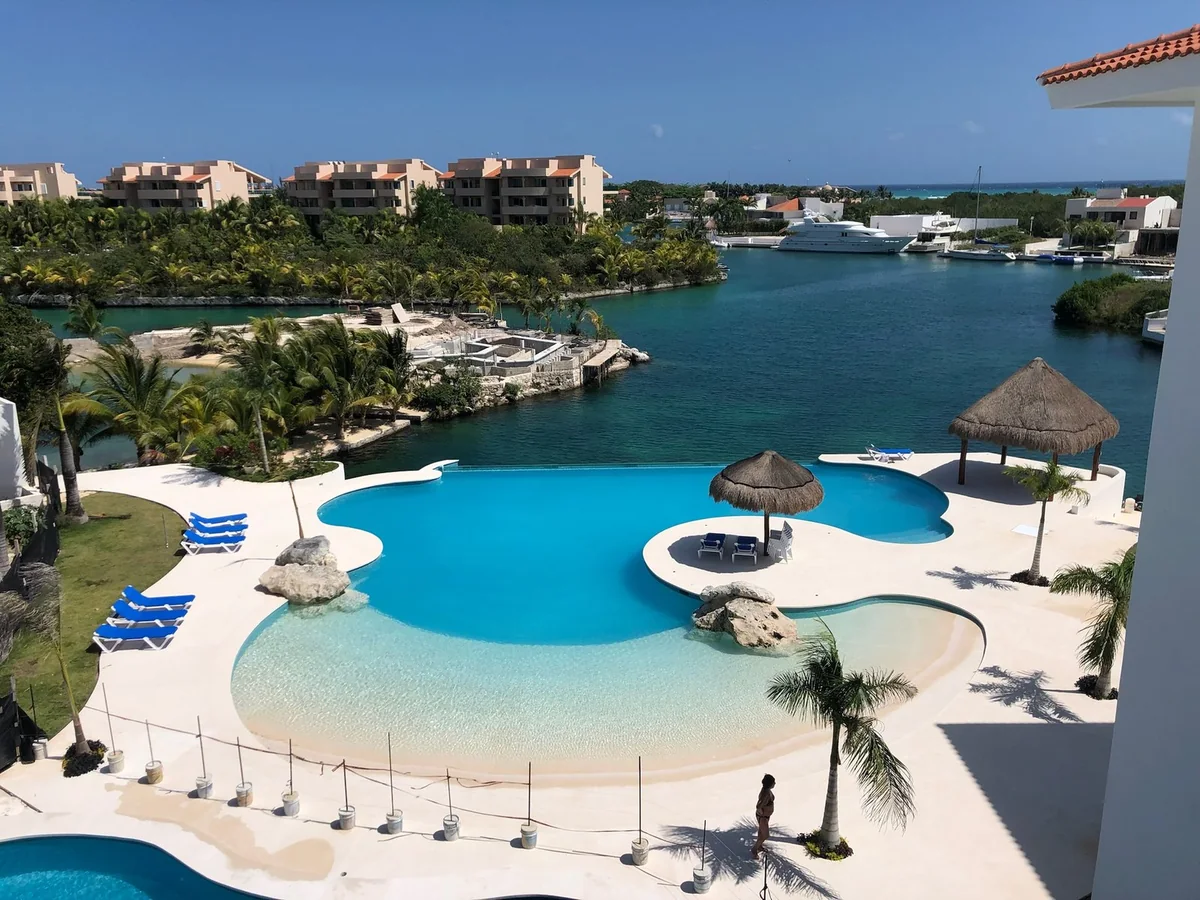 Puerto Aventuras: piscina con zona de playa y solárium en piedra de tono claro